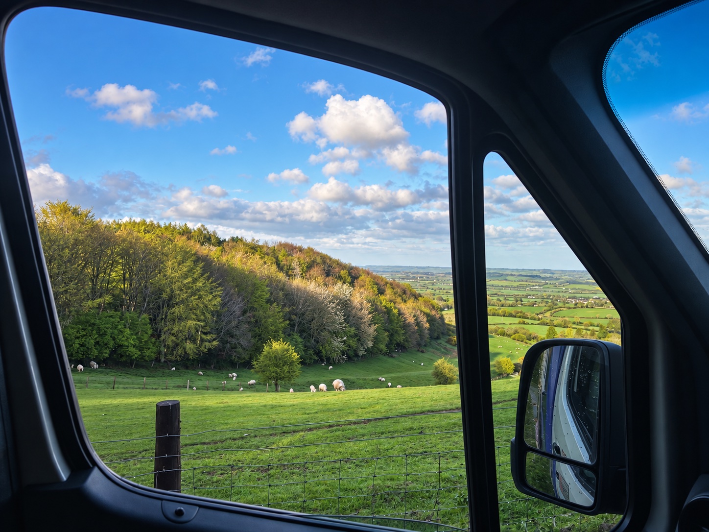 Green hills and sheep seen through the window of a delivery van